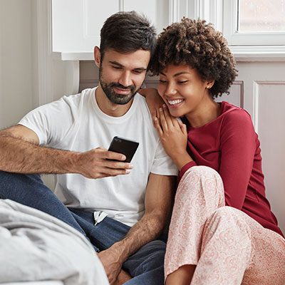 Young couple happily looking at their mobile phone